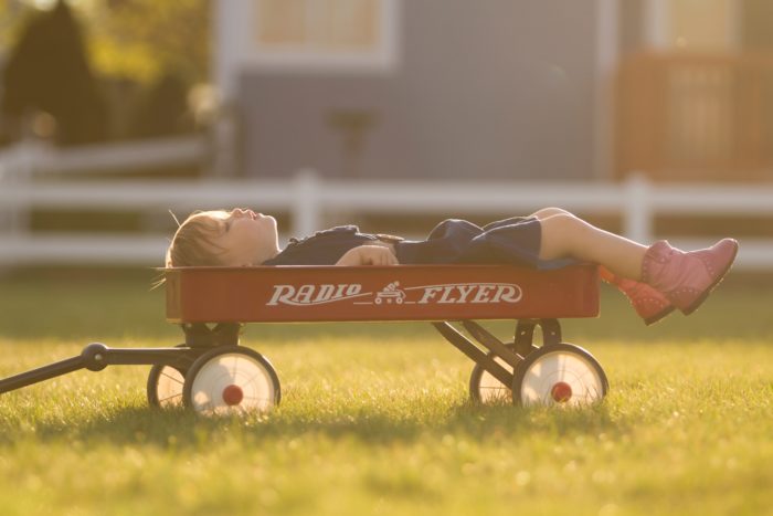 Enfant allongé sur une petite remorque dans un jardin