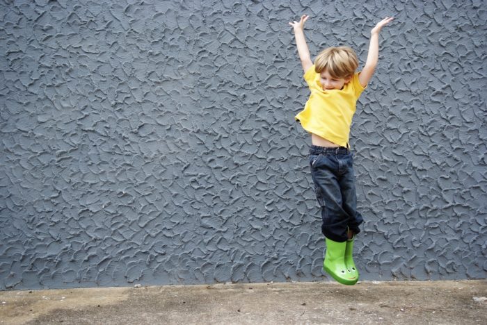 Enfant sautant les bras en l'air jouant en extérieur