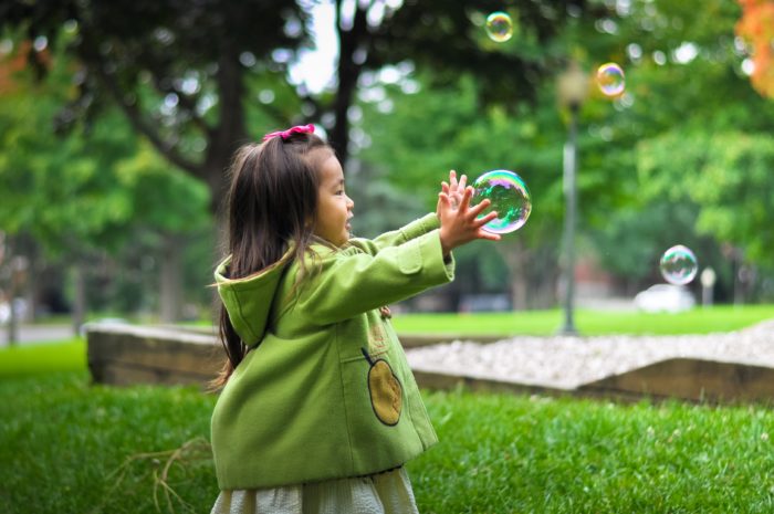 Enfant attrapant bulle de savon lors de sortie au parc