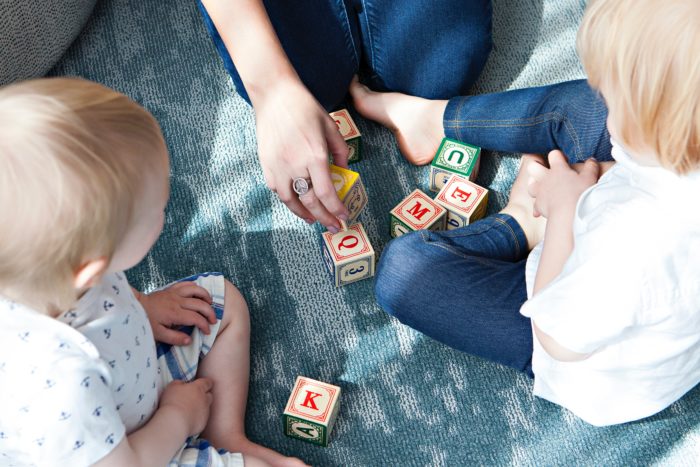 Enfant jouant avec des cubes accompagnés de leur nounou