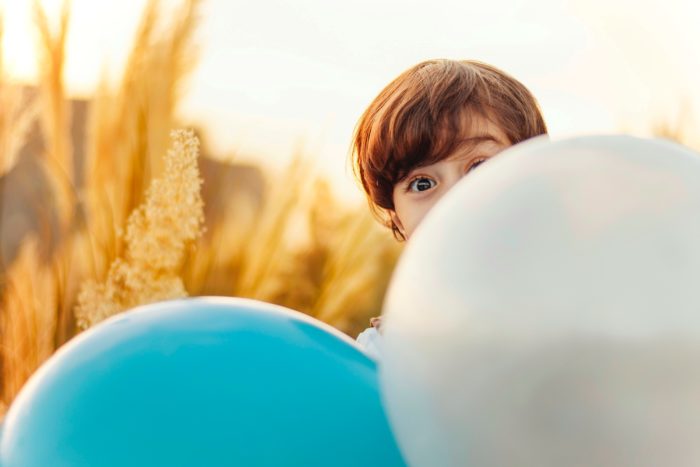 Enfant jouant à se cacher derrière un ballon lors d'une sortie nature
